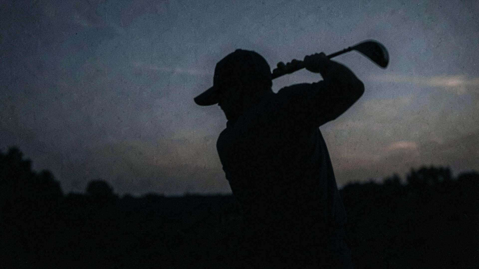 Golfer mid-swing at dusk